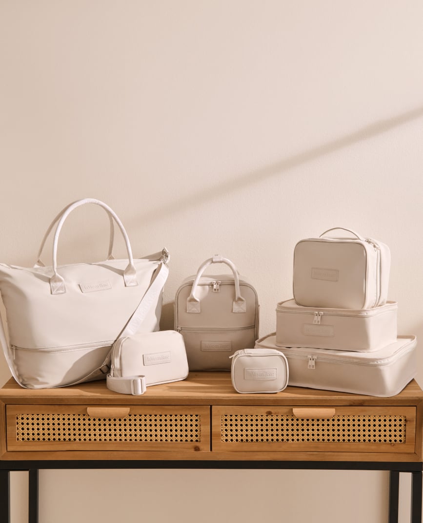 Seven beige travel accessories, including bags, pouches, and cases, placed on a table