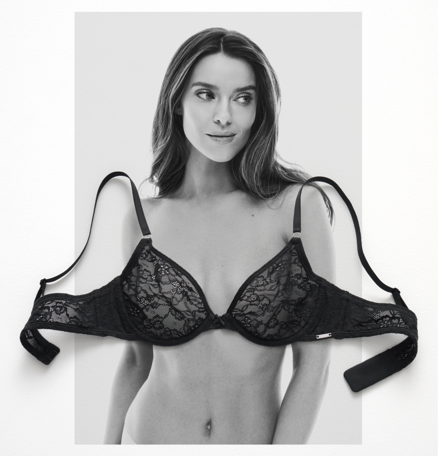 A black lace bra laid on a black-and-white photo of a model