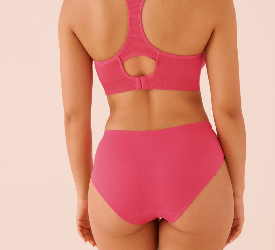 Three menstrual panties in red, black, and green displayed on a festive holiday setting.