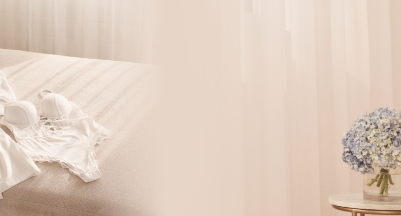 A white satin kimono and a white lace bodysuit laid out on a sofa