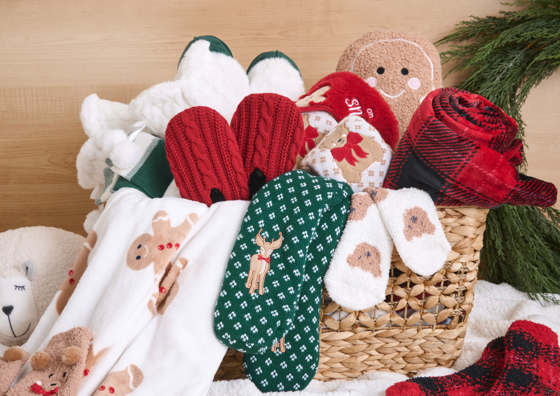 Basket filled with Christmas accessories: socks, slippers, and blankets.