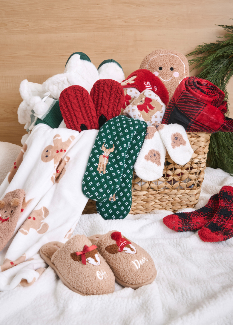 Basket filled with Christmas accessories: socks, slippers, and blankets.