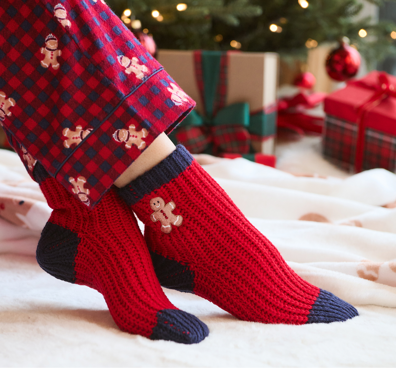 Model wearing red and navy socks with a gingerbread man pattern on the ankle.