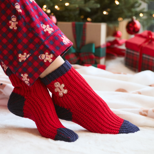 Model wearing red and navy socks with a gingerbread man pattern on the ankle.