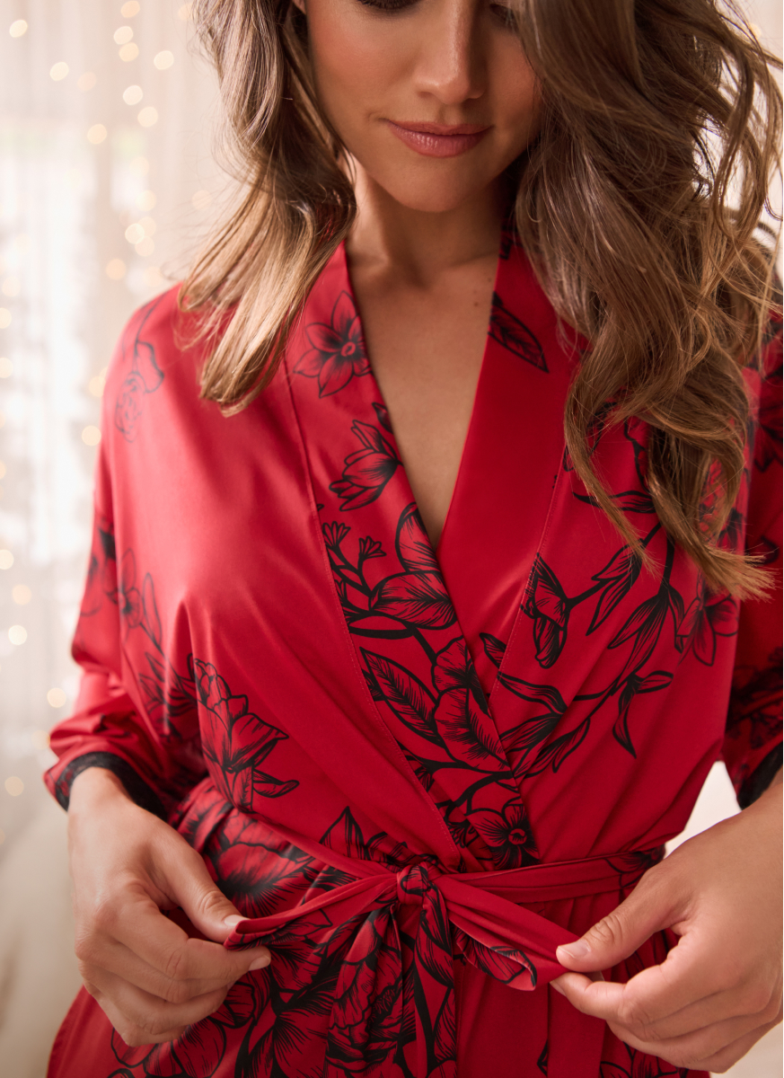 Model wearing a red satin kimono with black flowers.