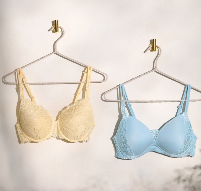 Deux soutiens-gorge mastectomie Muse suspendus sur des ceintres. Un jaune, l'autre bleu.